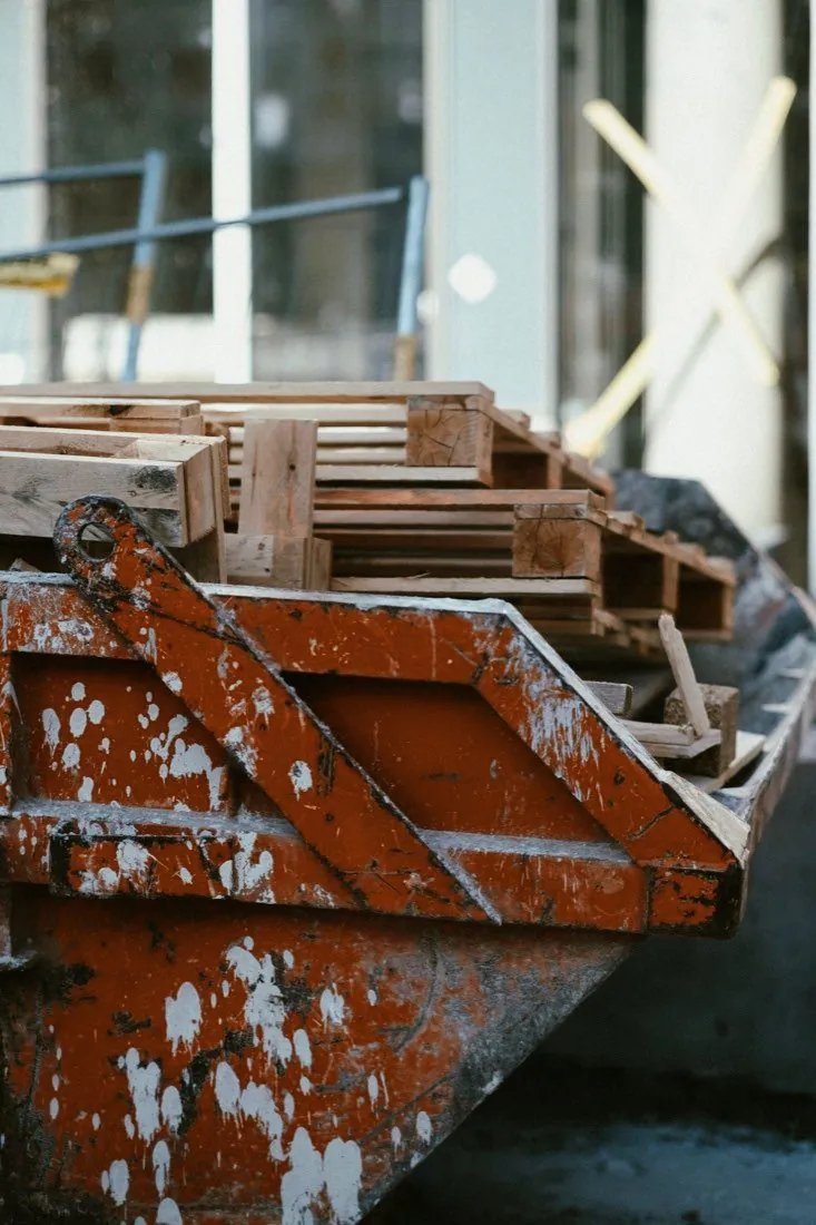 Steel roll-off container holding wood pallets and debris